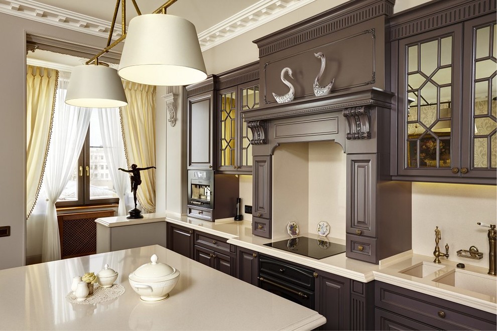 Klassisk inredning av ett kök, med en dubbel diskho, bruna skåp, beige stänkskydd, svarta vitvaror och en köksö