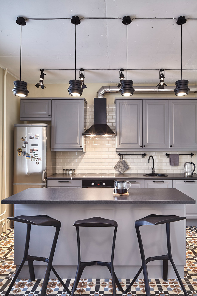 Idéer för att renovera ett funkis linjärt kök, med en nedsänkt diskho, luckor med upphöjd panel, grå skåp, vitt stänkskydd, stänkskydd i tunnelbanekakel, svarta vitvaror, en köksö och flerfärgat golv