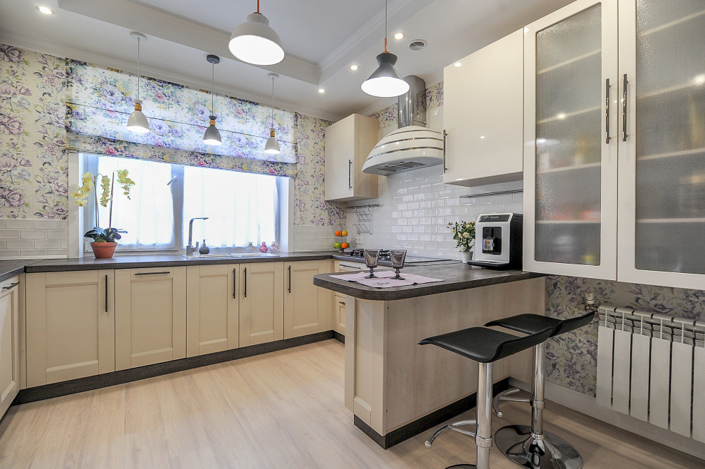 Lantlig inredning av ett mellanstort grå grått kök och matrum, med en dubbel diskho, luckor med infälld panel, vita skåp, laminatbänkskiva, vitt stänkskydd, stänkskydd i keramik, rostfria vitvaror, vinylgolv, en halv köksö och beiget golv