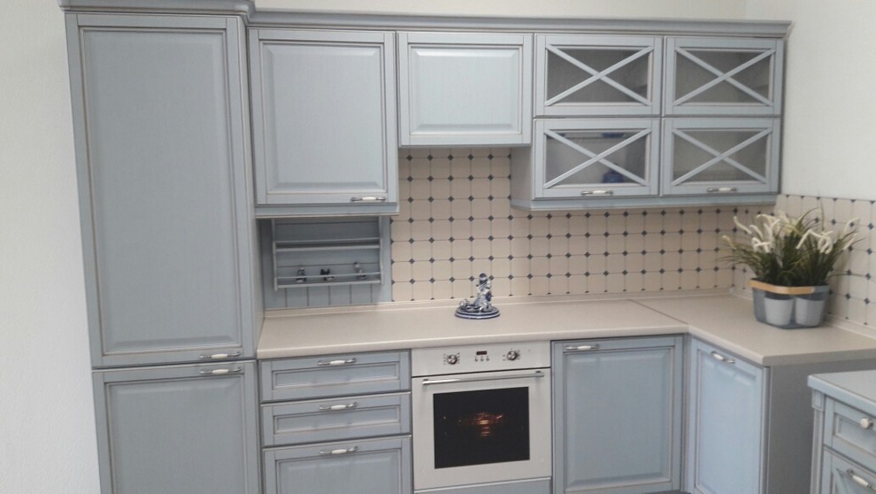Inredning av ett minimalistiskt mellanstort l-kök, med luckor med upphöjd panel, laminatbänkskiva, beige stänkskydd, vita vitvaror och grå skåp