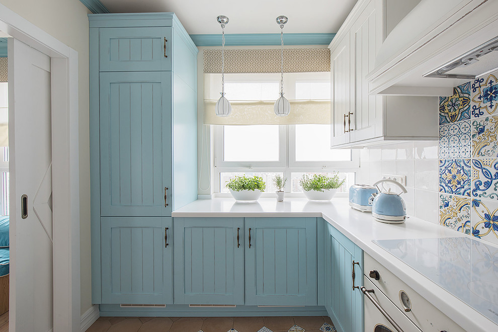 Ejemplo de cocinas en U marinero cerrado con armarios con paneles empotrados, puertas de armario azules y encimeras blancas
