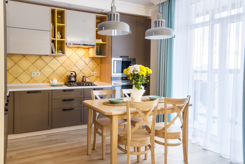 Contemporary l-shaped open plan kitchen in Other with recessed-panel cabinets, brown cabinets, yellow splashback, stainless steel appliances, beige floors and white worktops.