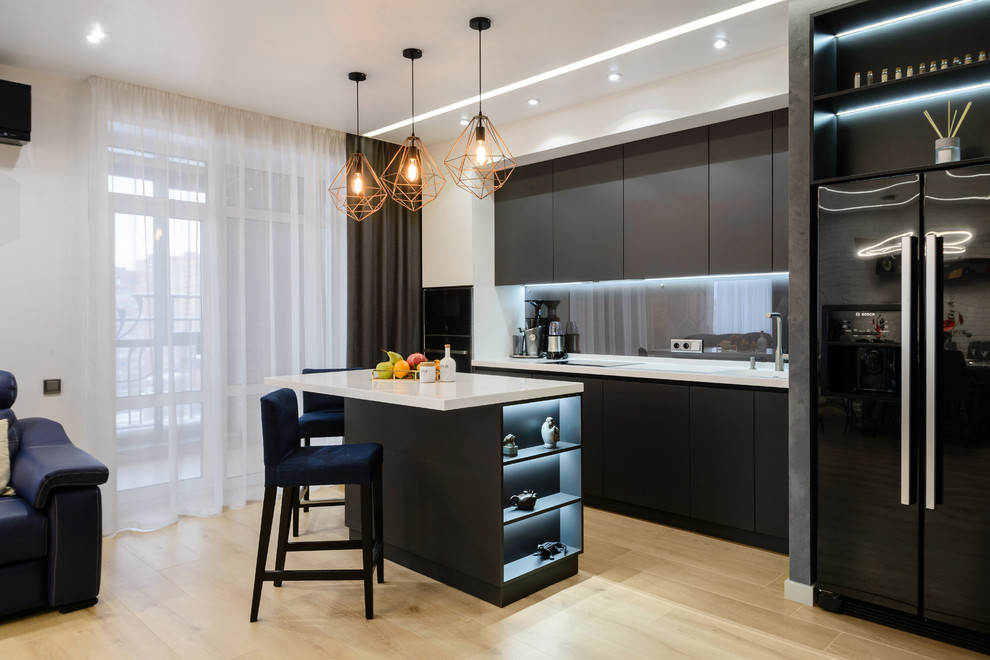 Идея дизайна: прямая кухня-гостиная в современном стиле с плоскими фасадами, черными фасадами, серым фартуком, фартуком из стекла, светлым паркетным полом, островом, бежевым полом и белой столешницей