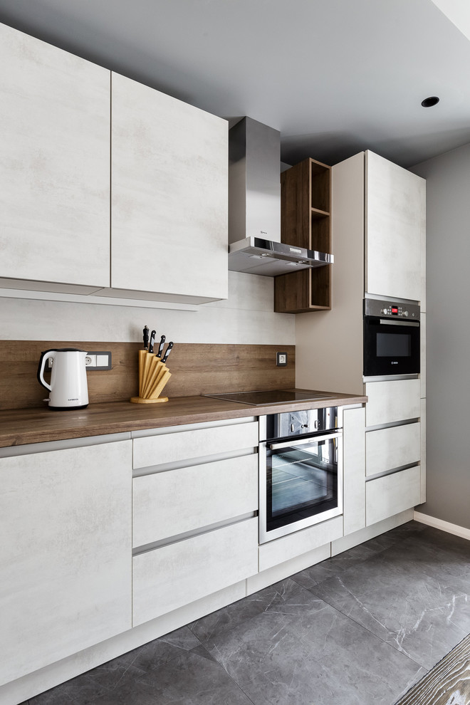 Источник вдохновения для домашнего уюта: кухня в современном стиле с плоскими фасадами, белыми фасадами, серым полом и коричневой столешницей