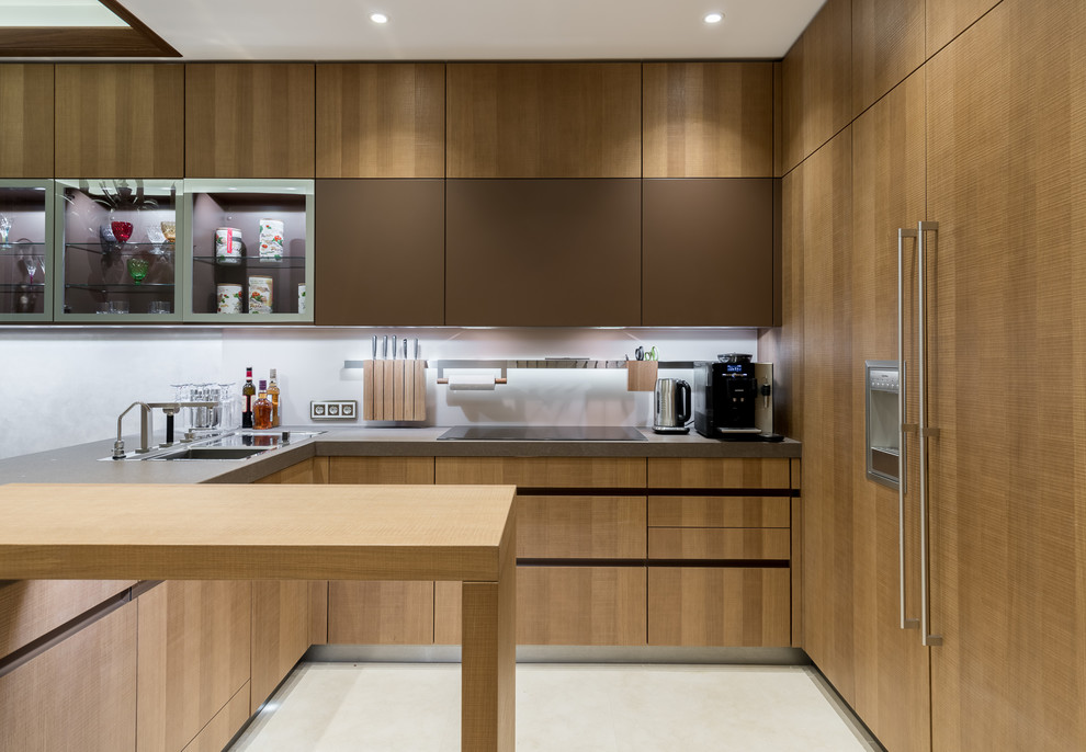Aménagement d'une cuisine encastrable moderne en L et bois foncé fermée avec un placard à porte plane, un plan de travail en béton, une crédence blanche, une péninsule et un sol blanc.