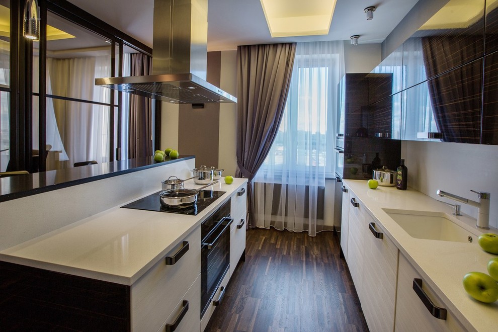 Diseño de cocina contemporánea de tamaño medio cerrada con salpicadero blanco, suelo marrón y puertas de armario beige
