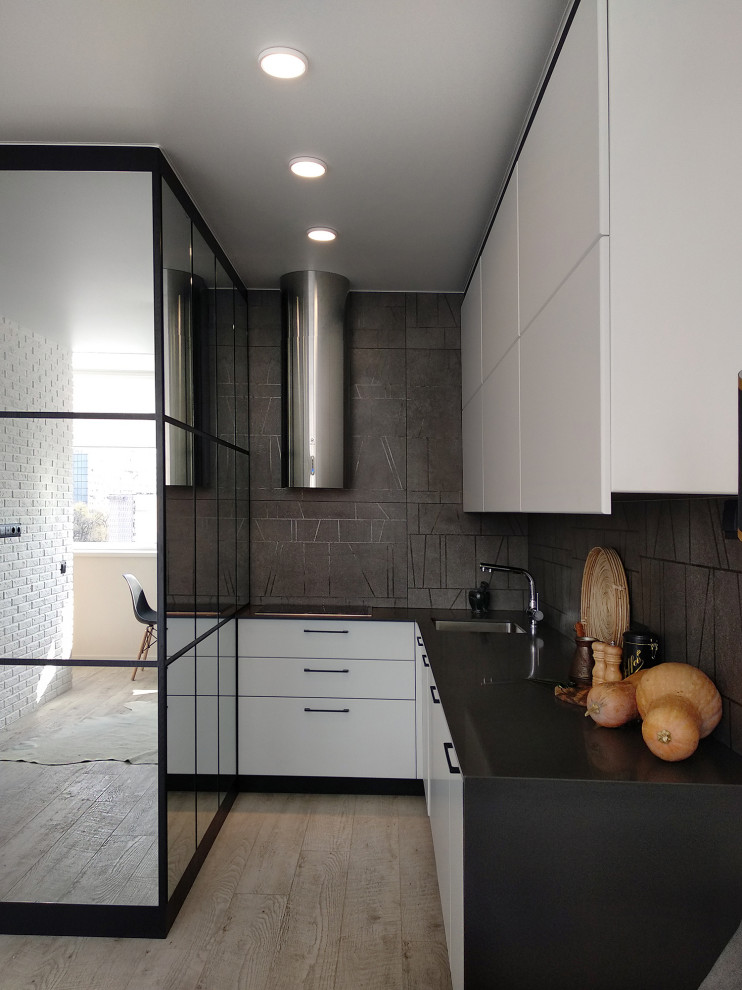 Exemple d'une petite cuisine tendance en L avec un évier encastré, un placard à porte plane, des portes de placard blanches, une crédence grise, aucun îlot, un sol gris et plan de travail noir.