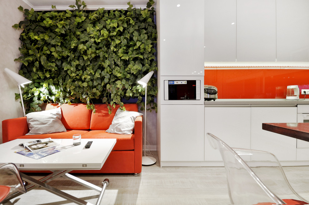 Ejemplo de cocina contemporánea con armarios con paneles lisos, puertas de armario blancas, electrodomésticos blancos, suelo de madera clara y salpicadero naranja