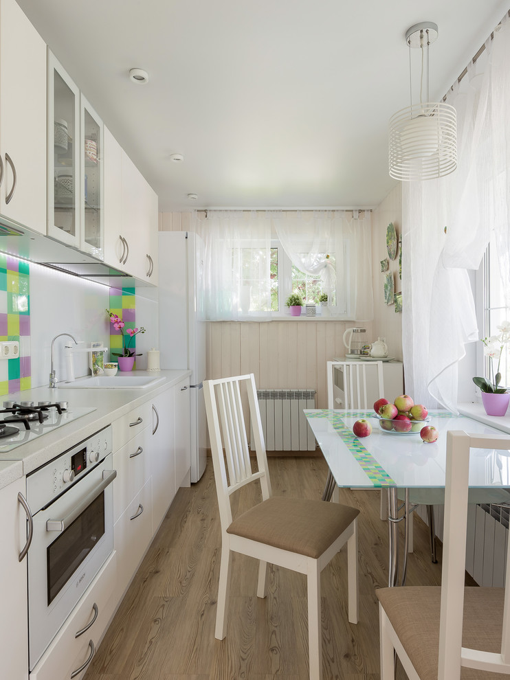 Ispirazione per una piccola cucina lineare contemporanea chiusa con paraspruzzi bianco, paraspruzzi con lastra di vetro, pavimento in vinile, pavimento beige e top bianco