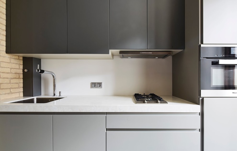 Foto di una cucina design con ante lisce, ante grigie e paraspruzzi bianco