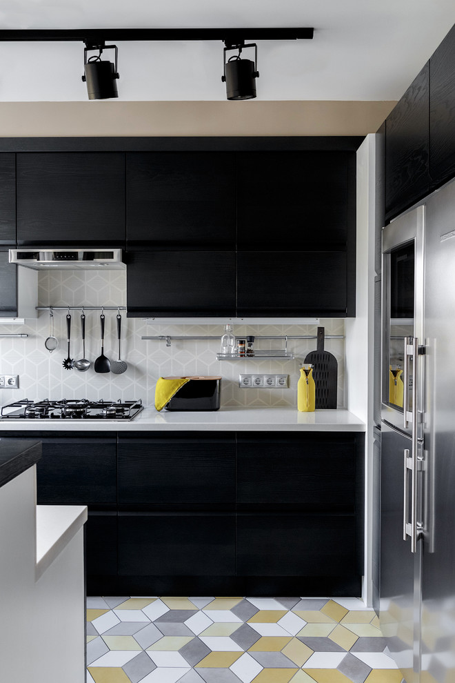 На фото: п-образная кухня-гостиная в современном стиле с плоскими фасадами, черными фасадами, серым фартуком, техникой из нержавеющей стали, полуостровом и разноцветным полом с