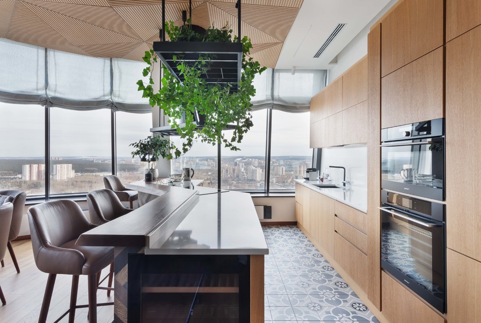 Свежая идея для дизайна: прямая кухня в современном стиле с обеденным столом, плоскими фасадами, светлыми деревянными фасадами и островом - отличное фото интерьера