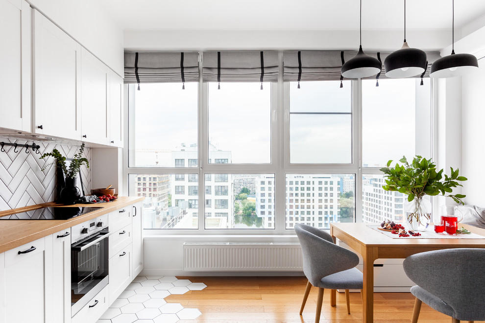 This is an example of a scandi single-wall kitchen in Moscow with a built-in sink, wood worktops, white splashback, porcelain splashback, ceramic flooring, no island and white floors.