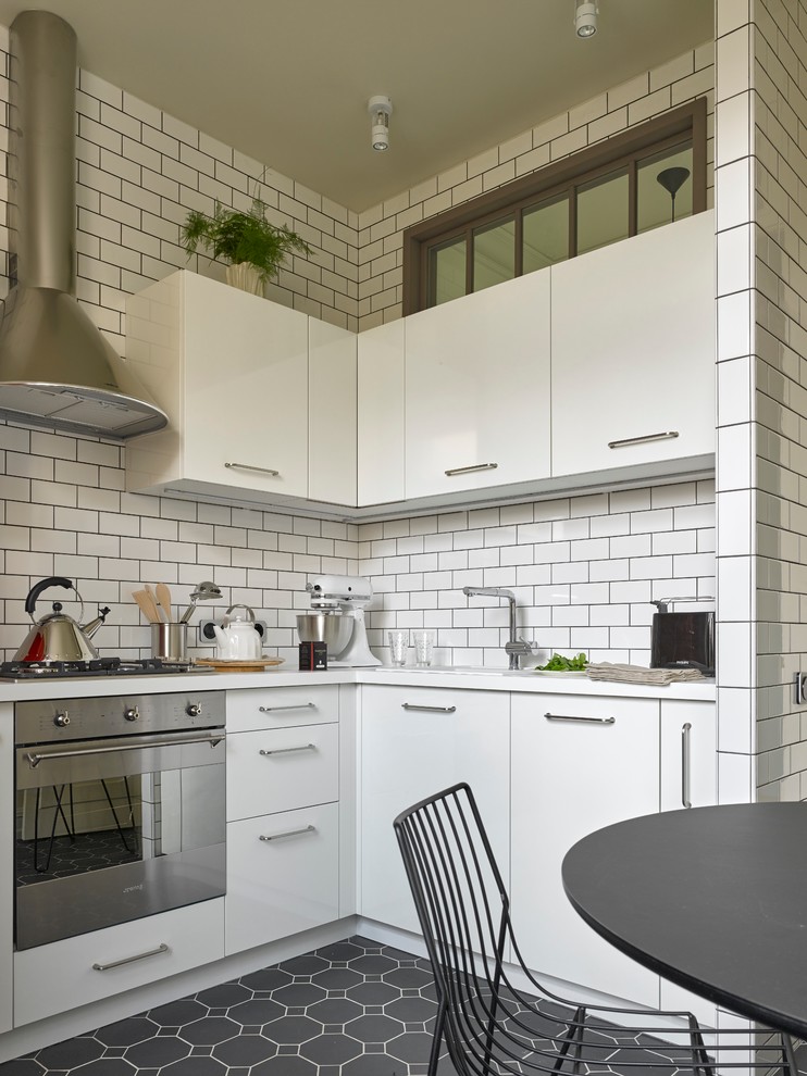 Moderne Wohnküche ohne Insel in L-Form mit flächenbündigen Schrankfronten, weißen Schränken, Küchenrückwand in Weiß, Rückwand aus Metrofliesen, Küchengeräten aus Edelstahl und Keramikboden in Moskau