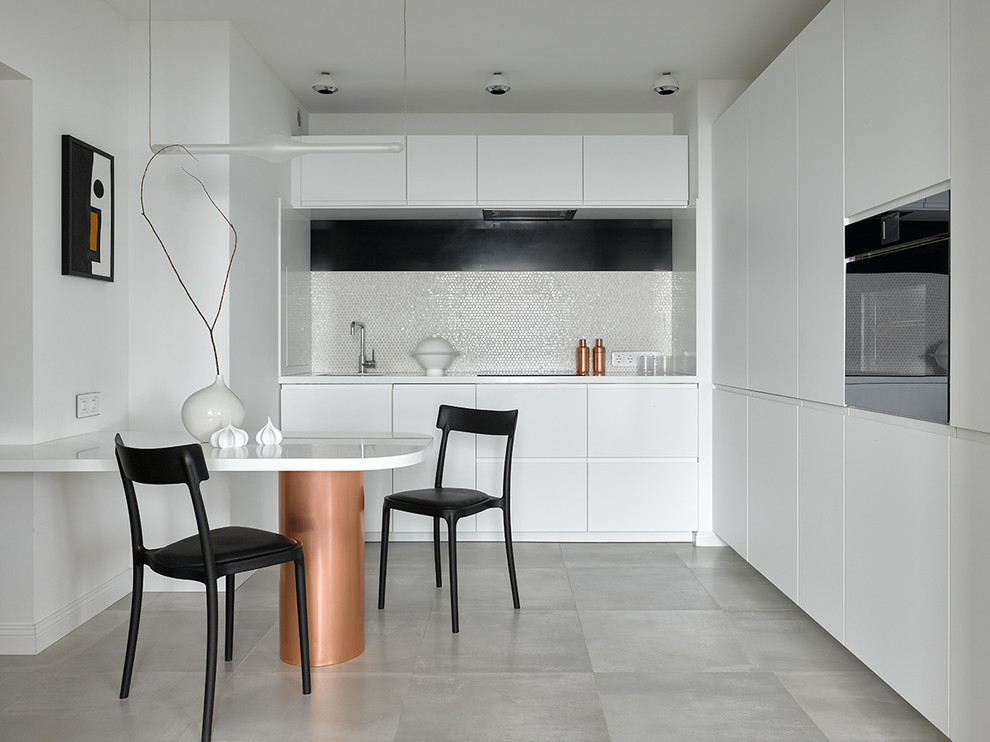 Medium sized contemporary l-shaped kitchen/diner in Moscow with a submerged sink, flat-panel cabinets, white splashback, mosaic tiled splashback, black appliances, no island, grey floors and white worktops.