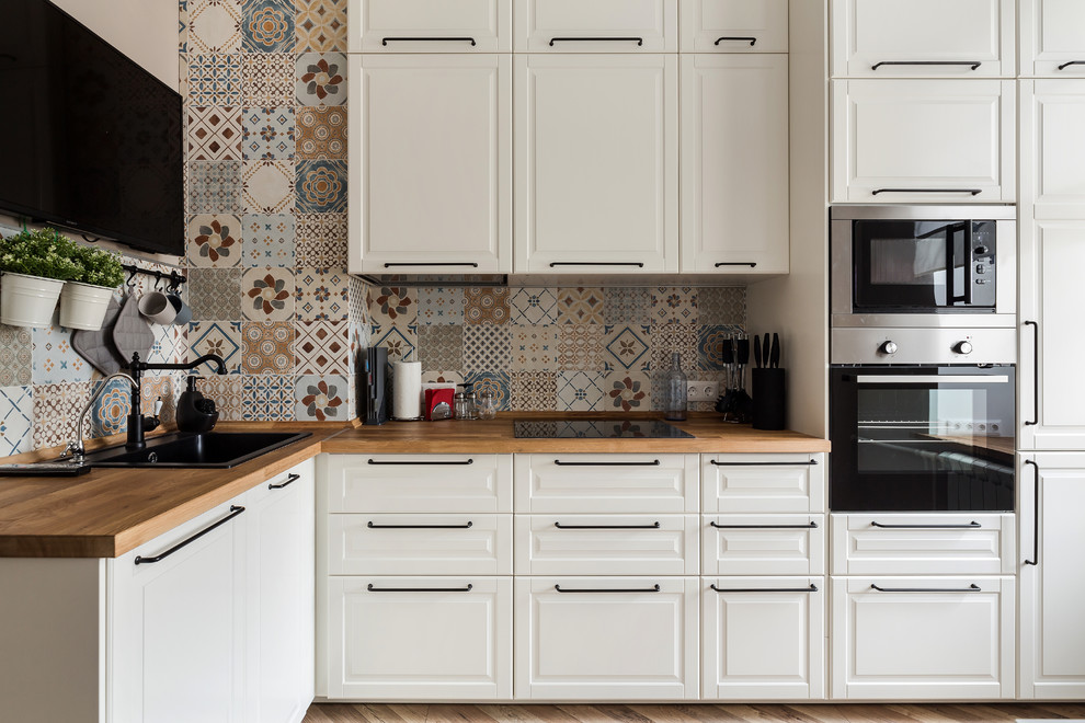 Photo of a traditional l-shaped kitchen in Saint Petersburg with a built-in sink, raised-panel cabinets, white cabinets, wood worktops and multi-coloured splashback.