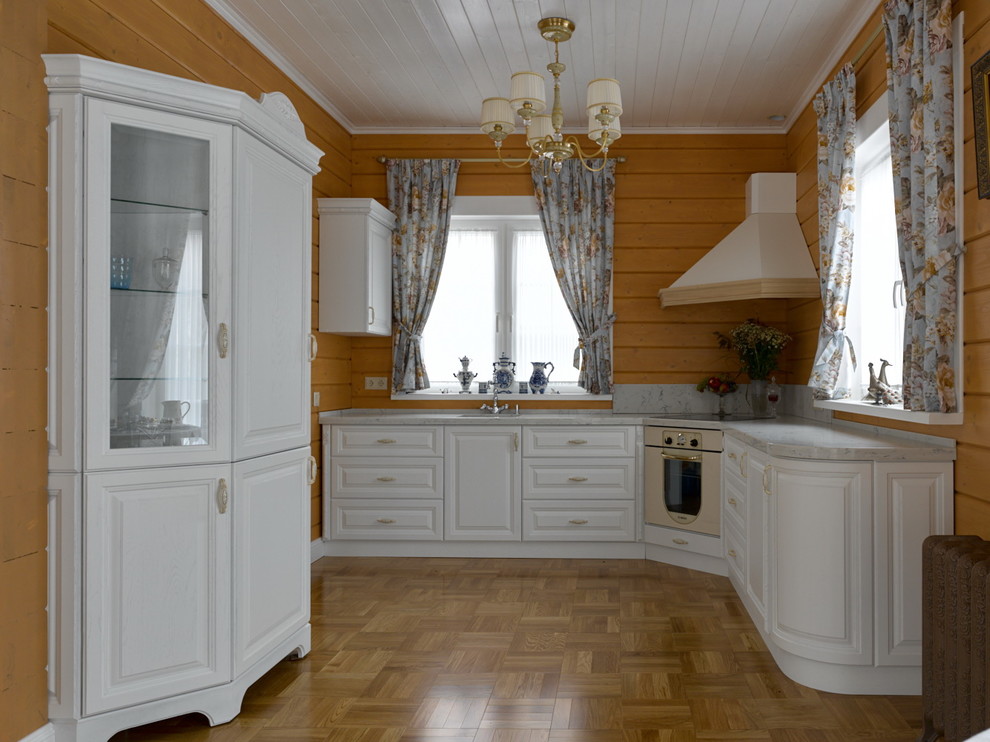 Design ideas for a medium sized traditional l-shaped kitchen/diner in Moscow with a submerged sink, raised-panel cabinets, white cabinets, engineered stone countertops, marble splashback, medium hardwood flooring and white worktops.