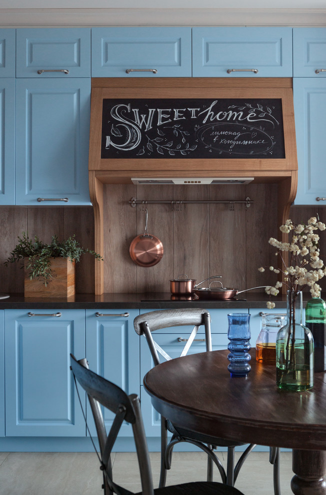 Стильный дизайн: кухня в современном стиле с фасадами с выступающей филенкой, синими фасадами, коричневым фартуком, черной столешницей и акцентной стеной - последний тренд