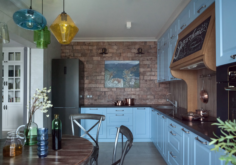 Immagine di una cucina design con lavello da incasso, ante con bugna sagomata, ante blu, pavimento grigio e top nero