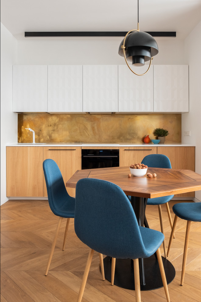 Small contemporary single-wall kitchen/diner in Moscow with flat-panel cabinets, medium wood cabinets, metallic splashback, black appliances, medium hardwood flooring, no island, brown floors and white worktops.