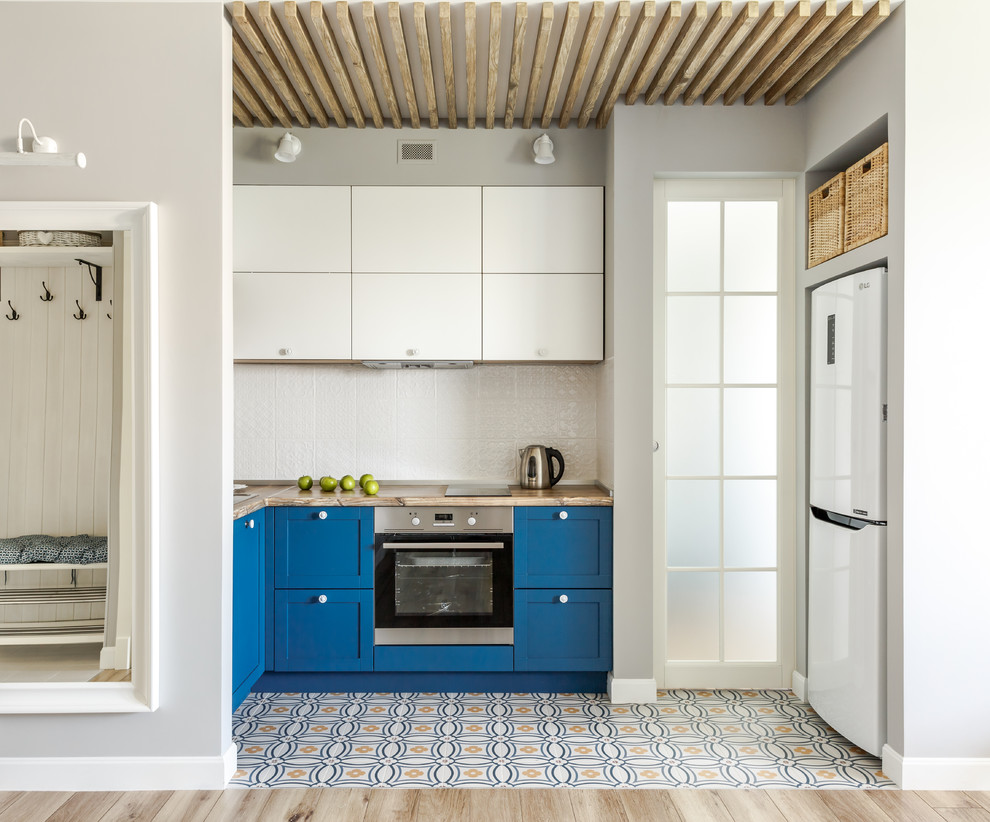Свежая идея для дизайна: п-образная кухня-гостиная со шкафом над холодильником в скандинавском стиле с накладной мойкой, фасадами в стиле шейкер, синими фасадами, деревянной столешницей, белым фартуком, разноцветным полом, коричневой столешницей, белой техникой и красивой плиткой без острова - отличное фото интерьера