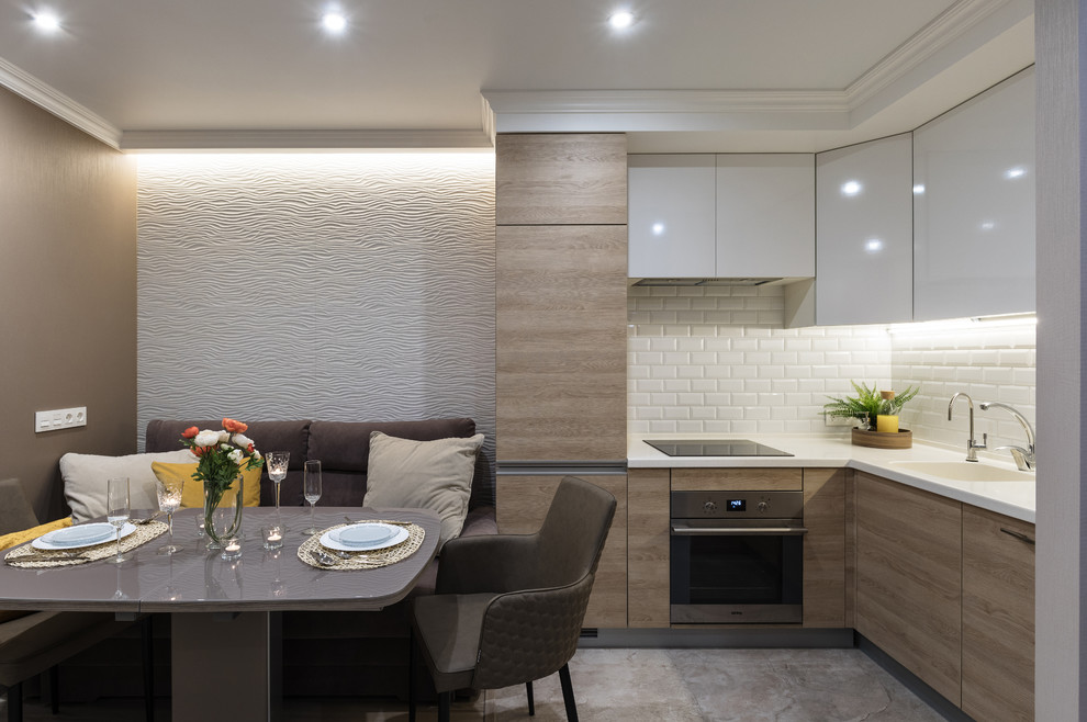 This is an example of a small contemporary l-shaped kitchen/diner in Saint Petersburg with a submerged sink, flat-panel cabinets, white cabinets, composite countertops, multi-coloured splashback, ceramic splashback, stainless steel appliances, porcelain flooring, no island and beige floors.