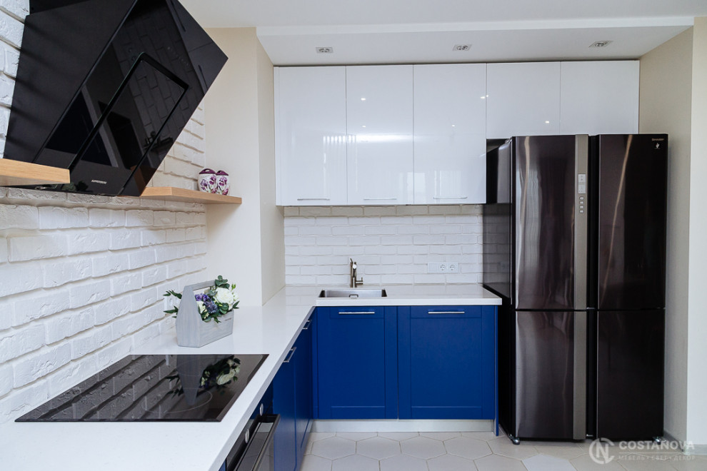 他の地域にある中くらいなトランジショナルスタイルのおしゃれなキッチン (アンダーカウンターシンク、落し込みパネル扉のキャビネット、青いキャビネット、人工大理石カウンター、白いキッチンパネル、レンガのキッチンパネル、黒い調理設備、セラミックタイルの床、白い床、白いキッチンカウンター) の写真