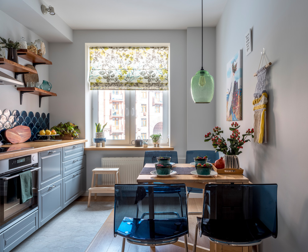 This is an example of a contemporary enclosed kitchen in Moscow with raised-panel cabinets, grey cabinets, wood worktops, blue splashback, ceramic splashback, stainless steel appliances, no island and brown worktops.