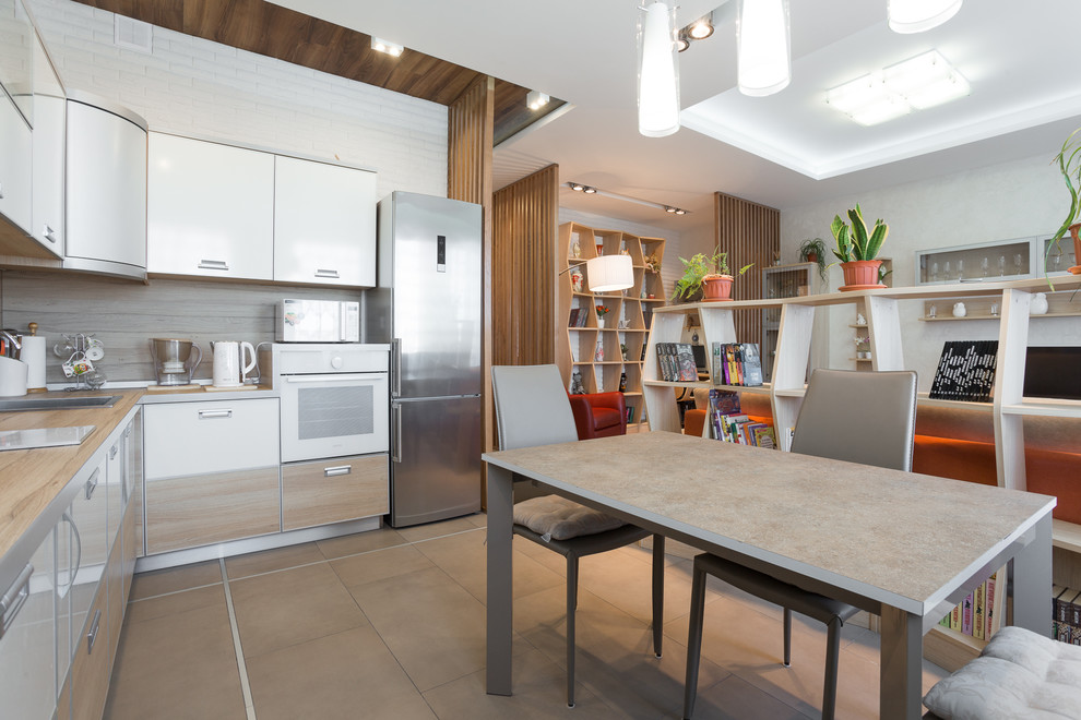 Идея дизайна: угловая кухня-гостиная среднего размера в скандинавском стиле с накладной мойкой, плоскими фасадами, коричневым фартуком и белой техникой без острова