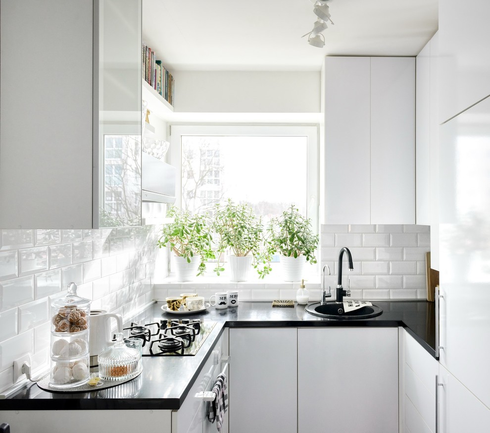 Стильный дизайн: маленькая п-образная, глянцевая кухня у окна в скандинавском стиле с накладной мойкой, плоскими фасадами и черно-белыми фасадами без острова для на участке и в саду - последний тренд