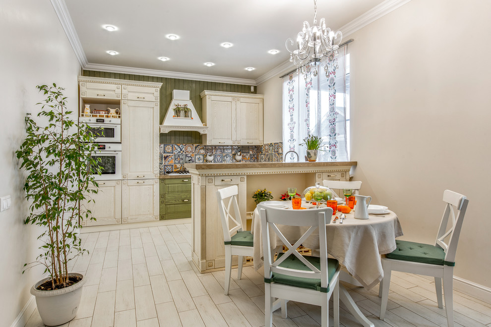 На фото: кухня в классическом стиле с разноцветным фартуком, светлым паркетным полом, обеденным столом, фасадами с утопленной филенкой, светлыми деревянными фасадами, белой техникой и полуостровом