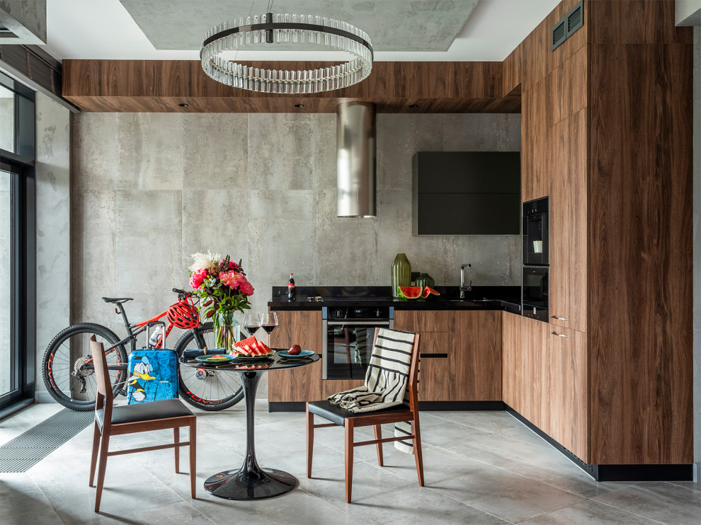 Moderne Wohnküche in L-Form mit flächenbündigen Schrankfronten, hellbraunen Holzschränken, schwarzen Elektrogeräten, zwei Kücheninseln, grauem Boden und schwarzer Arbeitsplatte in Moskau