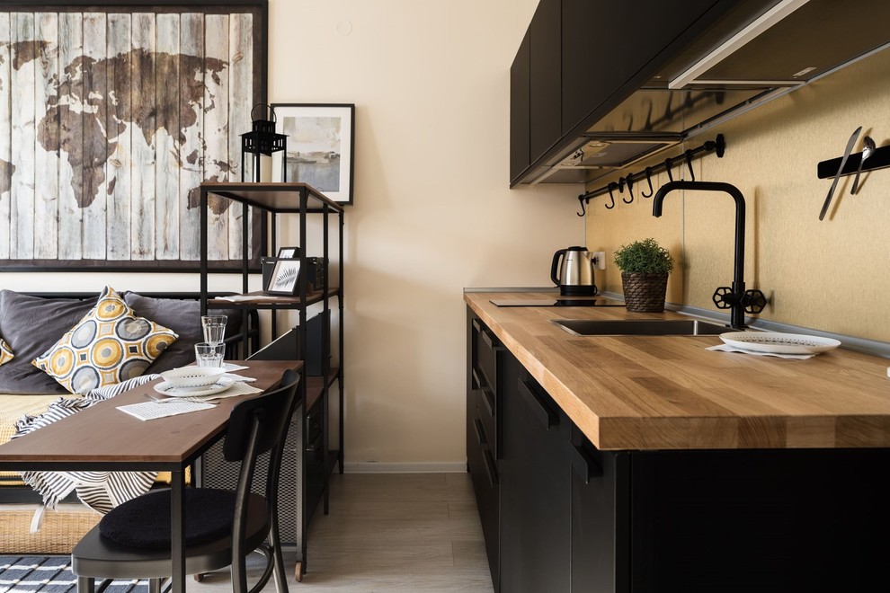 Esempio di una piccola cucina lineare con lavello da incasso, ante lisce, ante nere, top in legno, paraspruzzi beige, elettrodomestici neri, pavimento in laminato, nessuna isola e pavimento beige