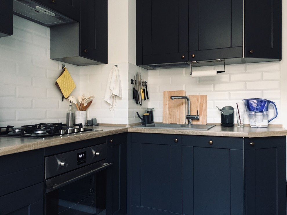 Immagine di una piccola cucina nordica con lavello sottopiano, ante grigie, paraspruzzi bianco, elettrodomestici neri, pavimento in gres porcellanato, nessuna isola e top marrone