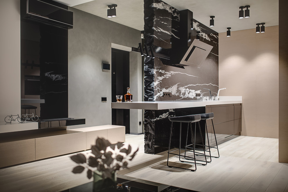 На фото: прямая кухня в современном стиле с черными фасадами, черным фартуком, светлым паркетным полом, бежевым полом и белой столешницей