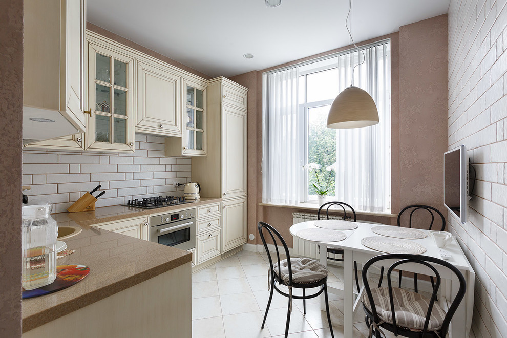 Design ideas for a small traditional l-shaped enclosed kitchen in Saint Petersburg with a built-in sink, raised-panel cabinets, beige cabinets, composite countertops, white splashback, ceramic splashback, coloured appliances, porcelain flooring, no island, beige floors and brown worktops.