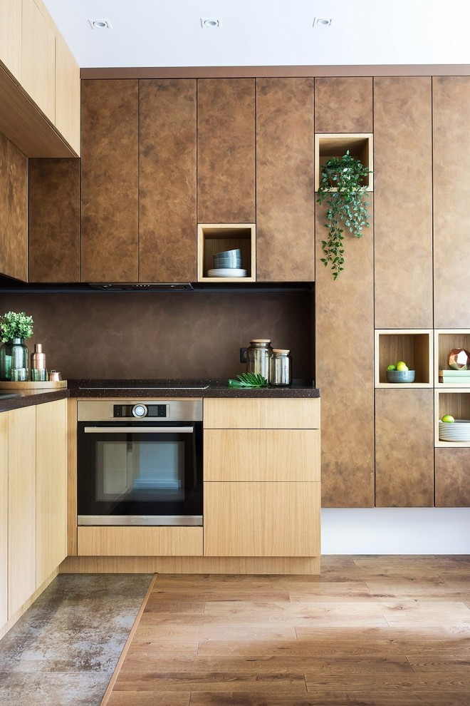На фото: угловая кухня в современном стиле с плоскими фасадами, коричневыми фасадами, коричневым фартуком, коричневым полом и двухцветным гарнитуром с