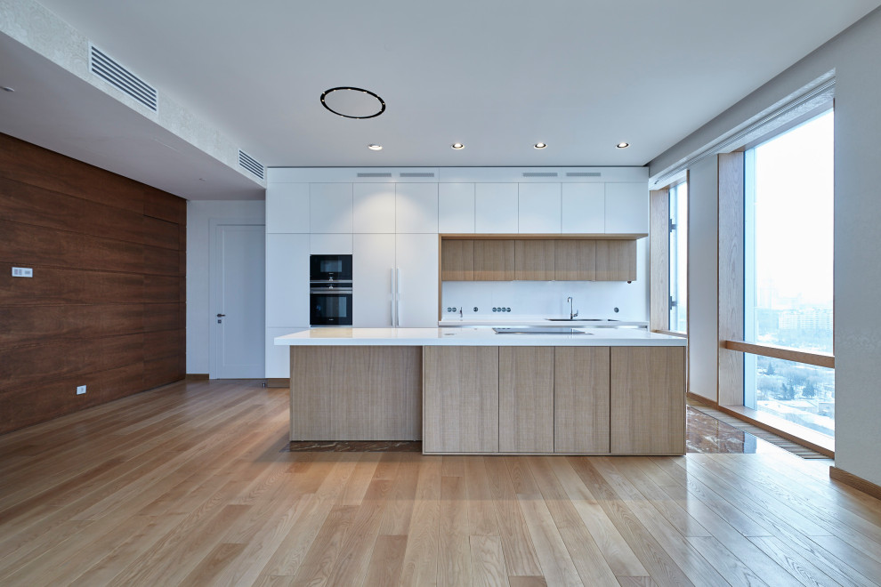 Foto di una grande cucina design con lavello a doppia vasca, ante bianche, paraspruzzi bianco, pavimento in laminato, pavimento marrone e top bianco