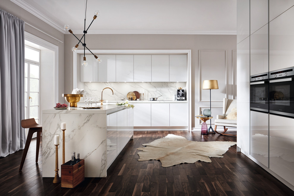 Foto de cocina comedor contemporánea de tamaño medio con puertas de armario blancas, salpicadero blanco, una isla, armarios con paneles lisos, suelo de madera oscura, suelo marrón y electrodomésticos de acero inoxidable