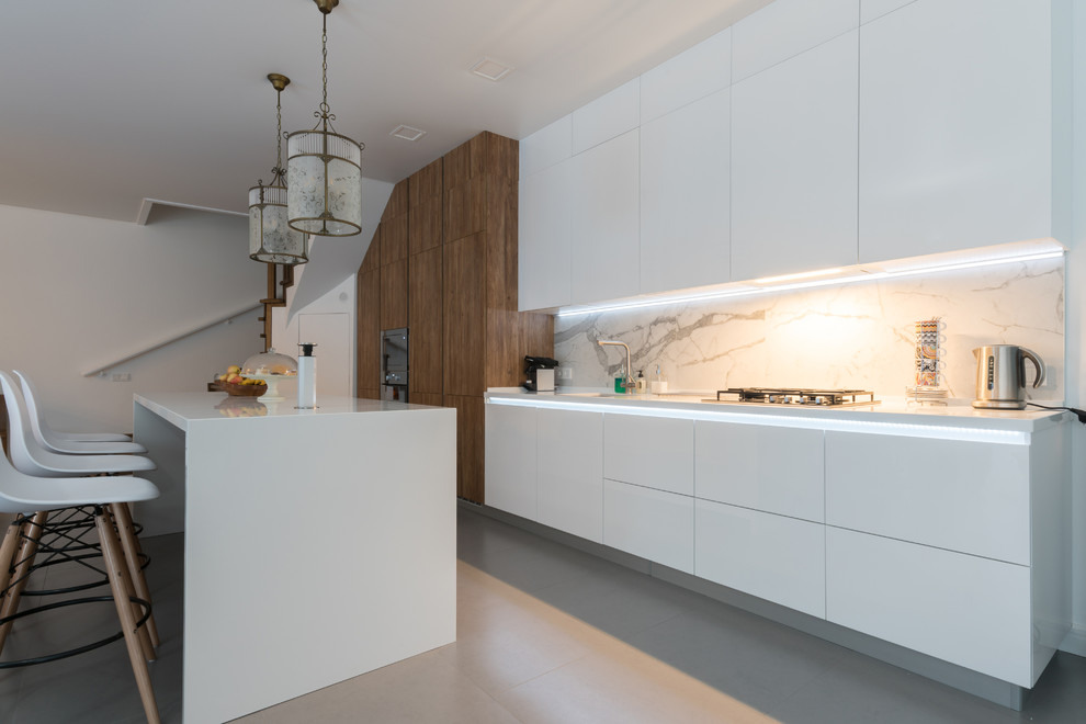 Exempel på ett stort modernt vit linjärt vitt kök med öppen planlösning, med en integrerad diskho, släta luckor, vita skåp, bänkskiva i kvarts, vitt stänkskydd, stänkskydd i porslinskakel, rostfria vitvaror, klinkergolv i porslin, en köksö och grått golv