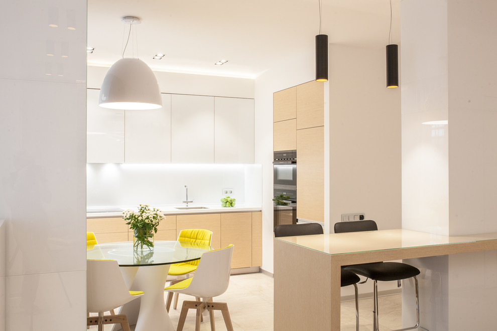 Inspiration for a contemporary open plan kitchen in Moscow with a submerged sink, flat-panel cabinets, white cabinets, white splashback, black appliances, beige floors and white worktops.