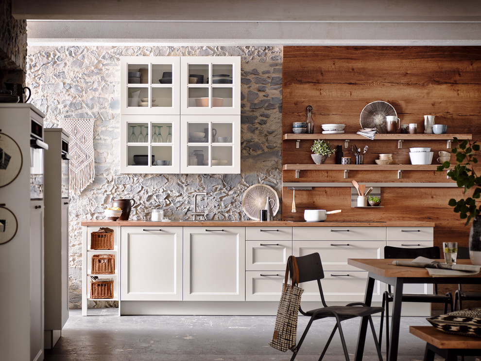Foto di una cucina classica di medie dimensioni con ante bianche, ante con riquadro incassato, top in legno, pavimento in cemento, nessuna isola e pavimento grigio