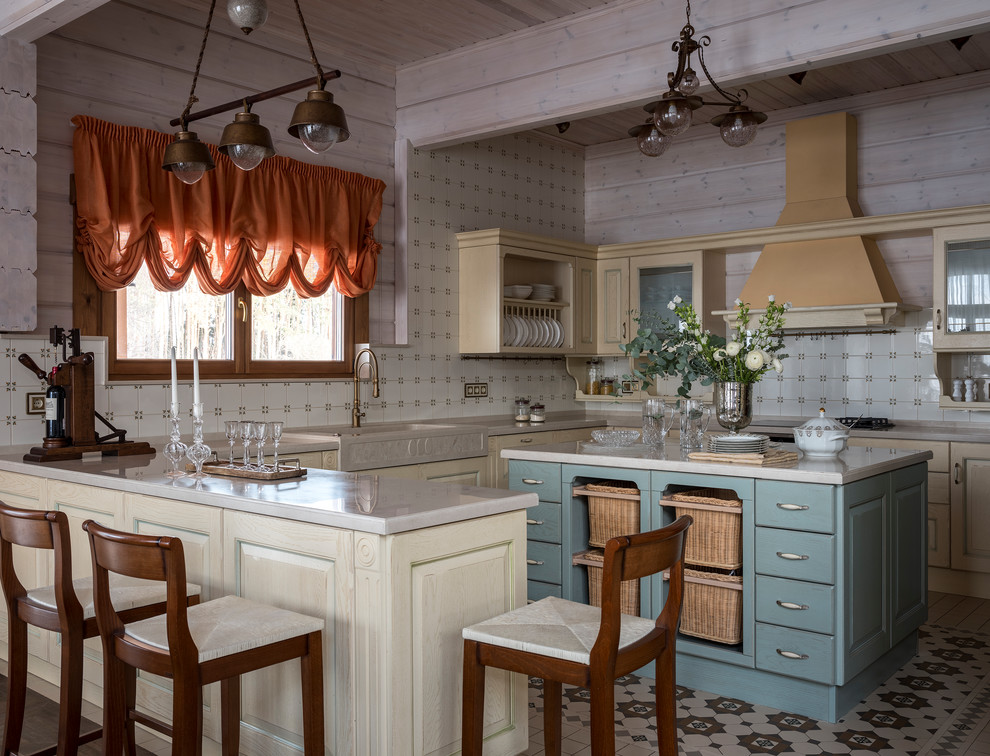 Lantlig inredning av ett beige beige u-kök, med en rustik diskho, luckor med upphöjd panel, beige skåp, beige stänkskydd, en köksö och flerfärgat golv