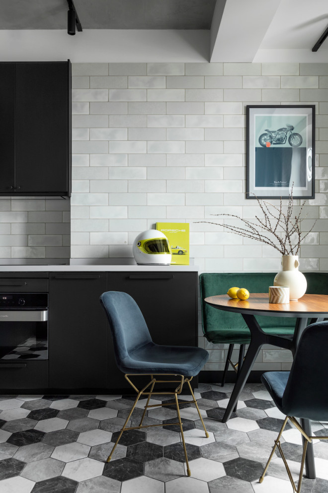 Foto de cocina contemporánea pequeña sin isla con armarios con paneles lisos, puertas de armario negras, salpicadero verde, electrodomésticos negros y suelo gris