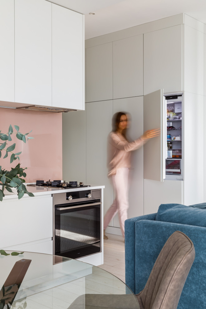 Свежая идея для дизайна: кухня-гостиная в современном стиле с плоскими фасадами, белыми фасадами и бежевым полом - отличное фото интерьера
