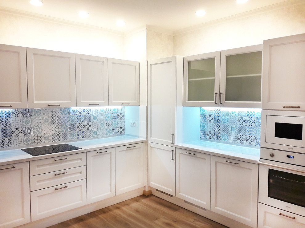 Inredning av ett modernt mellanstort kök, med en integrerad diskho, vita skåp, bänkskiva i koppar, blått stänkskydd, vita vitvaror och luckor med infälld panel