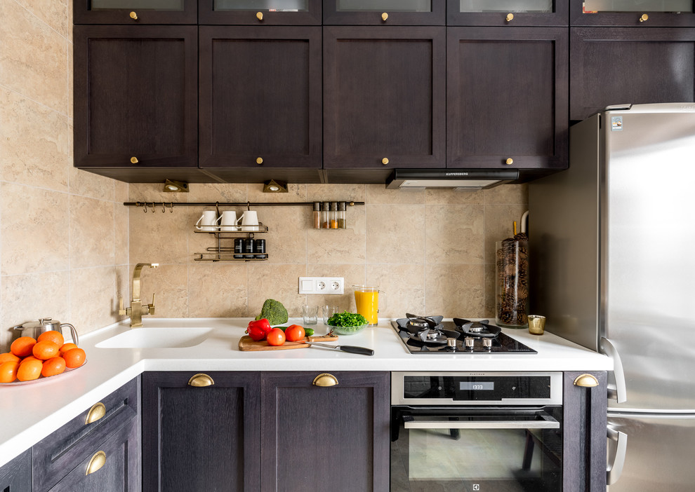 Photo of a small traditional kitchen in Moscow with an integrated sink, raised-panel cabinets, dark wood cabinets, composite countertops, beige splashback, ceramic splashback, stainless steel appliances, ceramic flooring and beige floors.