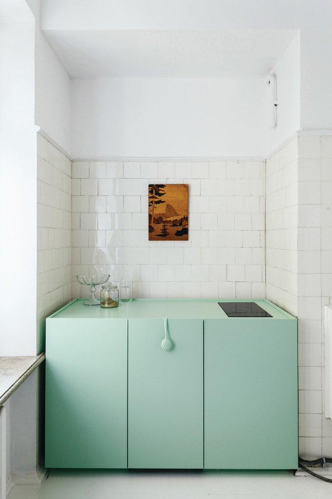Idée de décoration pour une cuisine design avec un placard à porte plane, des portes de placards vertess, une crédence blanche, un électroménager noir, un sol blanc et un plan de travail vert.