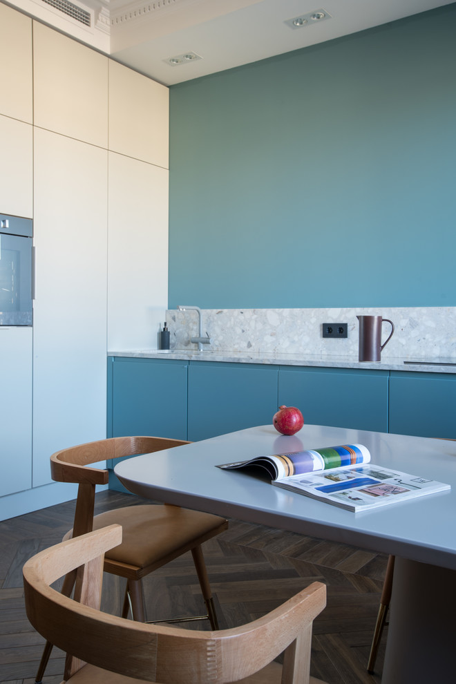 This is an example of a medium sized contemporary single-wall kitchen in Other with flat-panel cabinets, blue cabinets, blue splashback, medium hardwood flooring, no island, brown floors, grey worktops and terrazzo worktops.