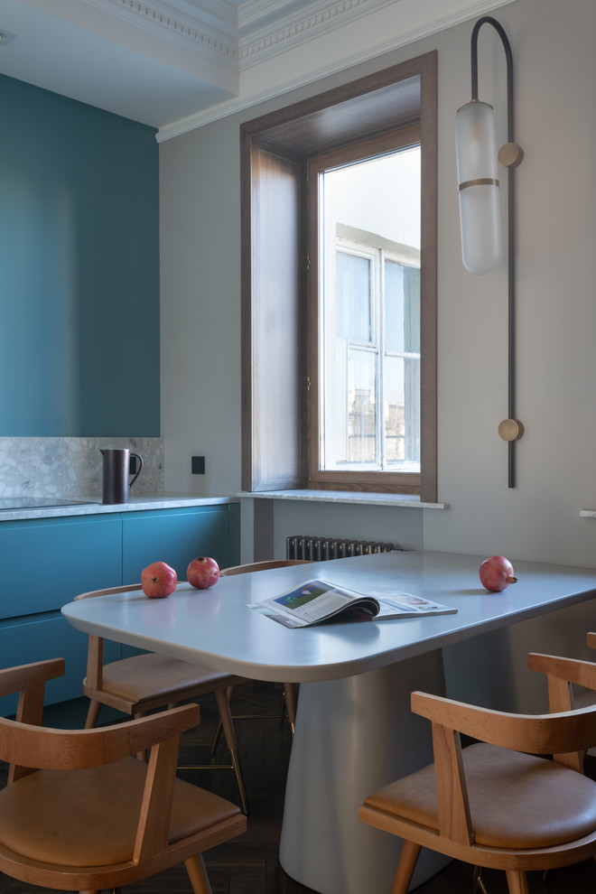 Cette photo montre une cuisine linéaire tendance de taille moyenne avec un placard à porte plane, des portes de placard bleues, une crédence bleue, aucun îlot, un plan de travail gris et un plan de travail en terrazzo.